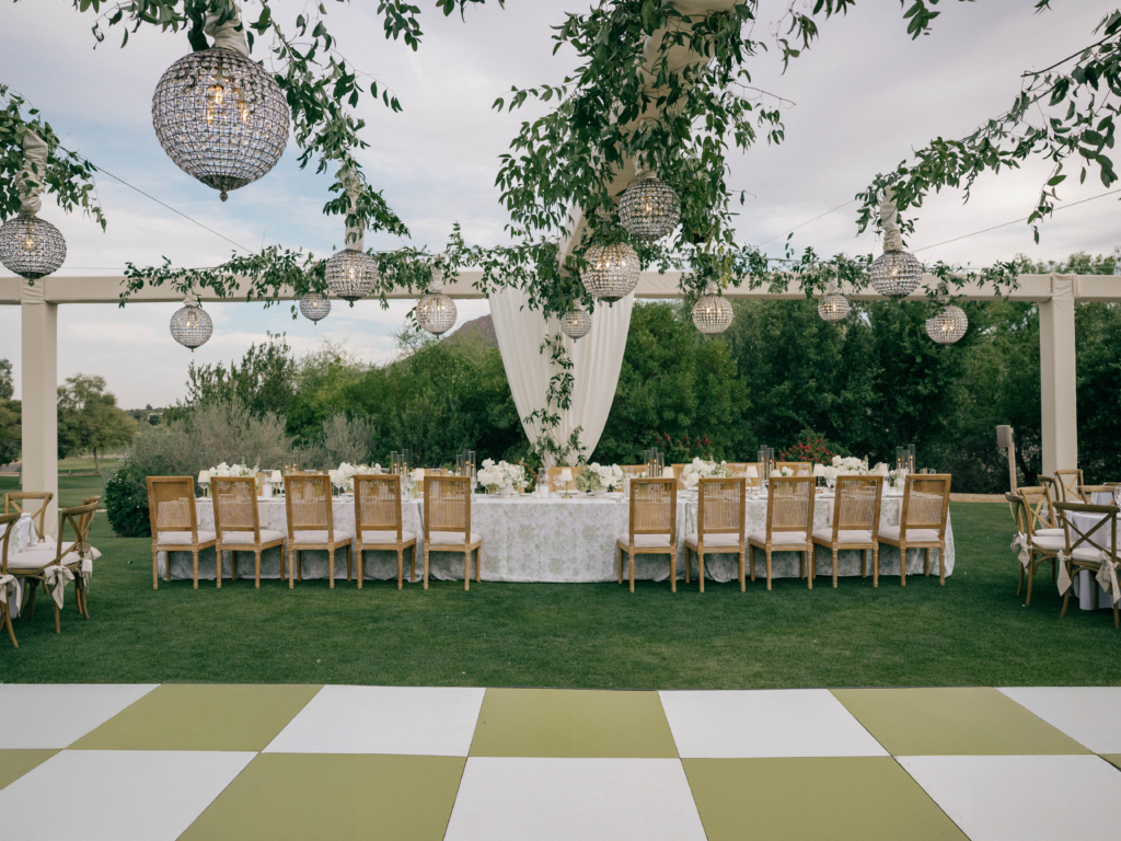 Luxury wedding produced by Centric Events and Rentals showcasing custom dance floor, truss structure, greenery on the truss, and custom chandelier installation