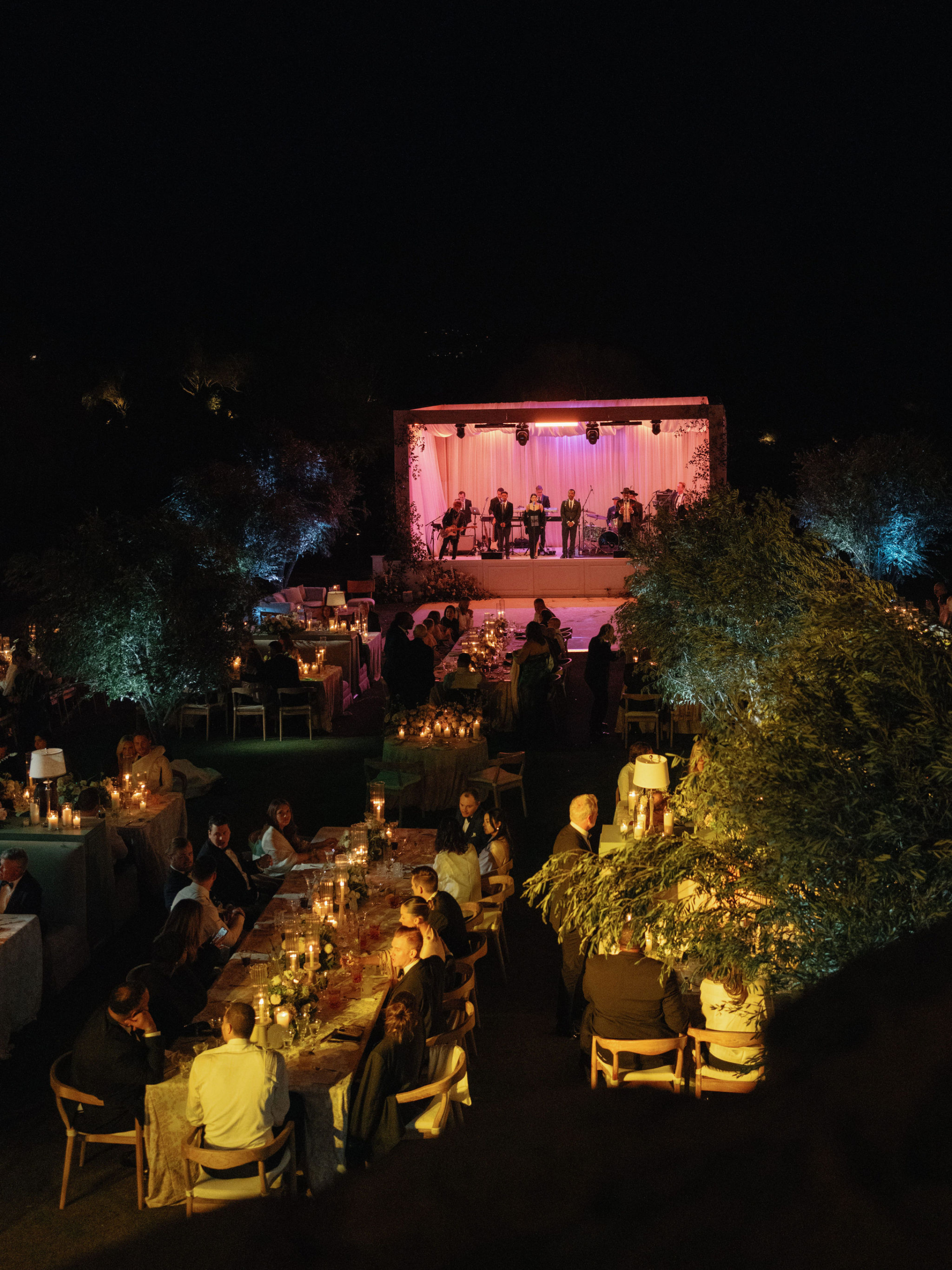 night time at a luxury wedding showcasing a wedding band with a custom design stage with trussing and wood facade and custom draping.