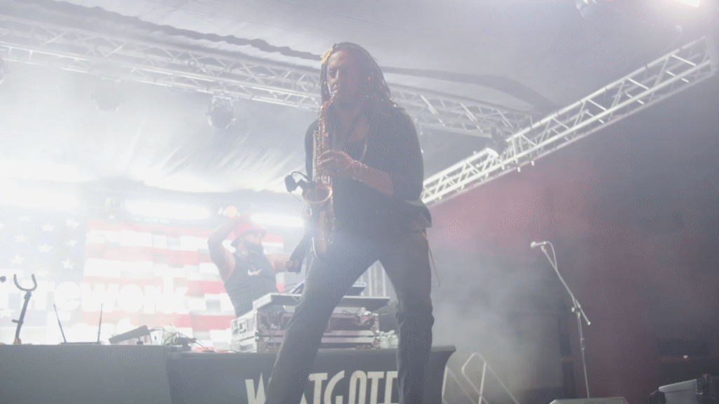 saxophone player on a stage surrounded by stage haze and bright lights at a concert