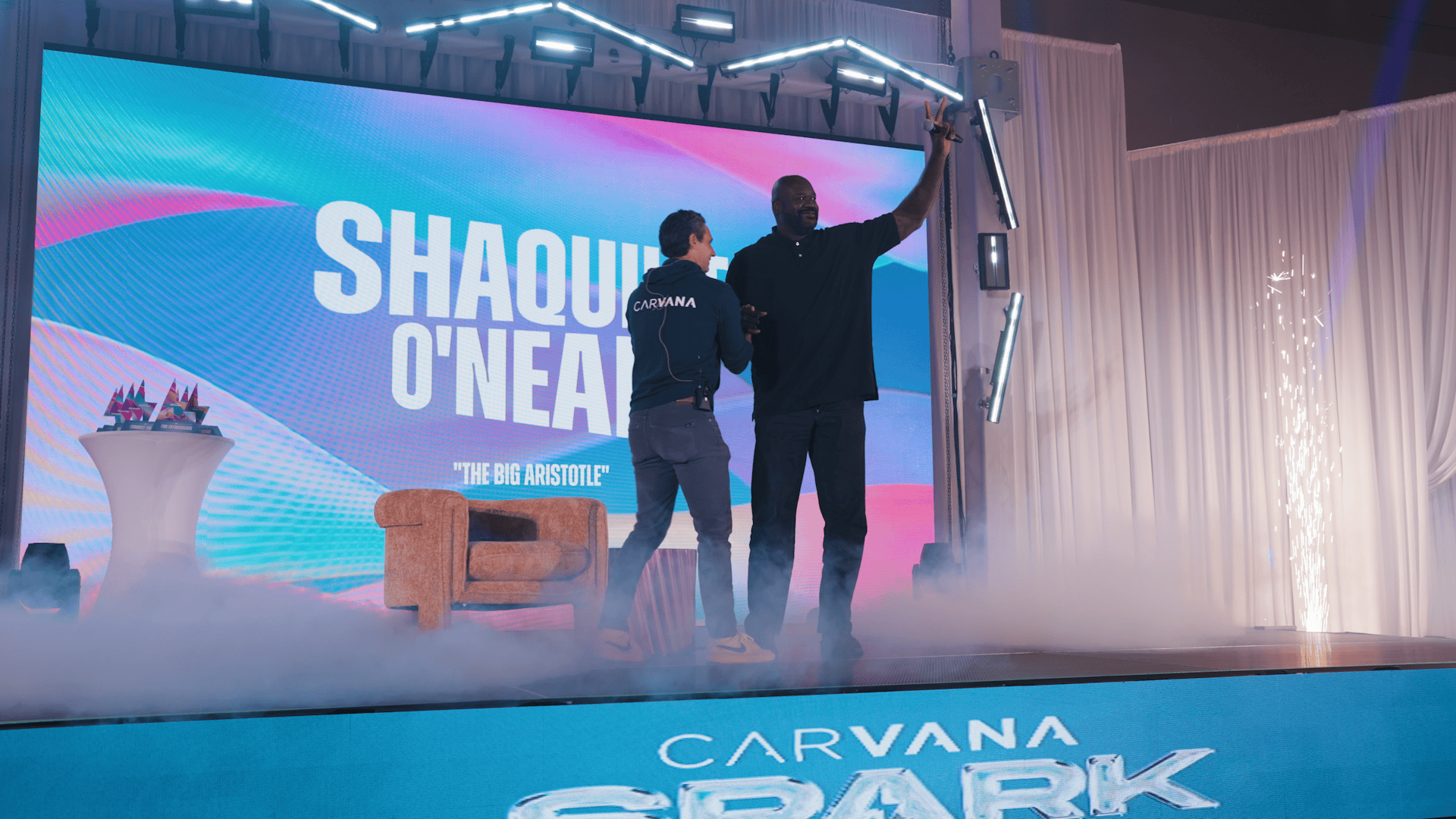 Shaquille O'Neal waving to the audience at Carvana SPARK with an LED video wall backdrop, dynamic LED stage skirt, and cold spark atmospherics