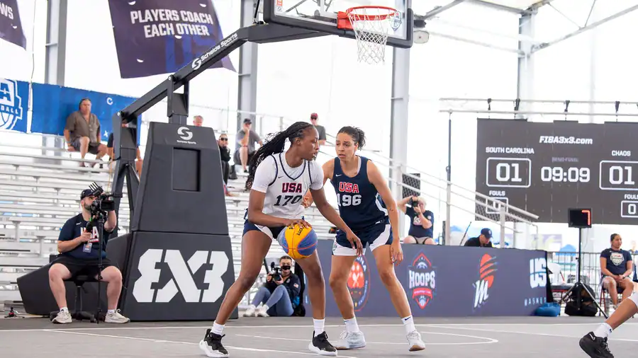 Two basketball players active on court with Centric's custom scoreboard jumbotron array suspended in the background and dynamic graphics looping on the boundary LED video walls.
